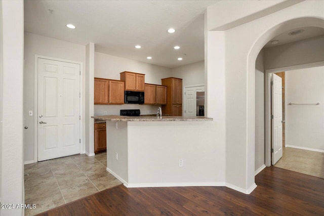 kitchen featuring black appliances, sink, and light hardwood / wood-style floors