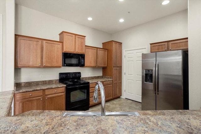 kitchen with black appliances, sink, light stone counters, and light tile patterned floors