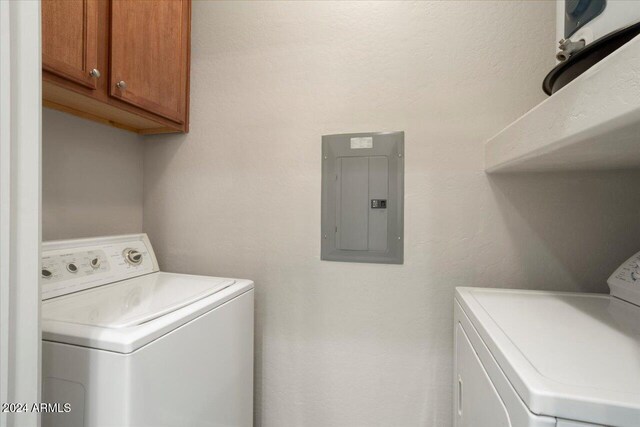 clothes washing area with electric panel, cabinets, and independent washer and dryer