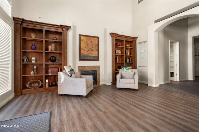 sitting room with dark wood-type flooring and a towering ceiling