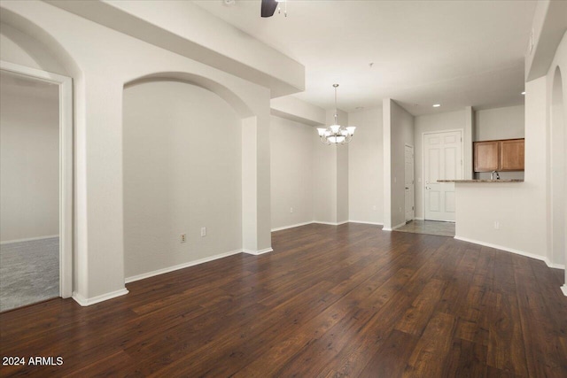 unfurnished living room featuring dark hardwood / wood-style floors and ceiling fan with notable chandelier