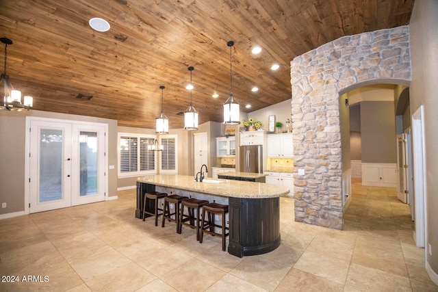 kitchen with arched walkways, a spacious island, freestanding refrigerator, wood ceiling, and a sink