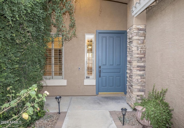 property entrance featuring stone siding and stucco siding