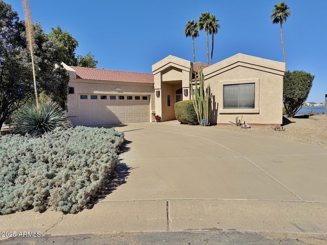 view of front of home with a tile roof, driveway, an attached garage, and stucco siding