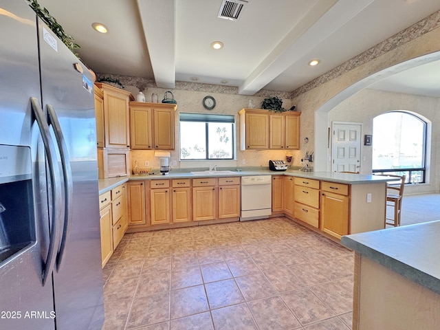 kitchen with white dishwasher, light brown cabinets, a peninsula, a sink, and stainless steel refrigerator with ice dispenser