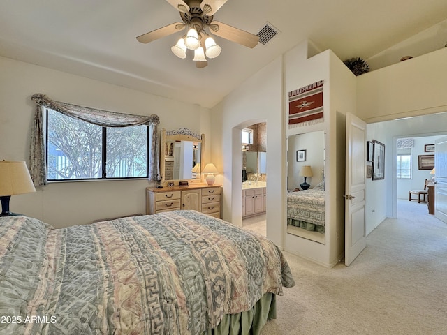 bedroom with connected bathroom, light colored carpet, a ceiling fan, visible vents, and vaulted ceiling