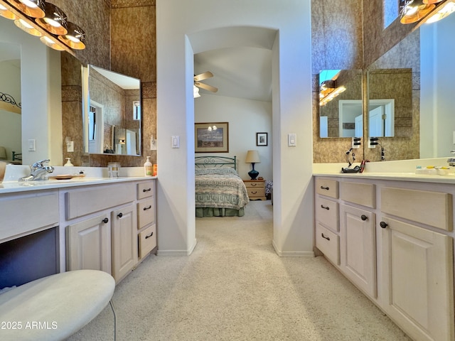 ensuite bathroom featuring lofted ceiling, two vanities, a ceiling fan, a sink, and ensuite bath