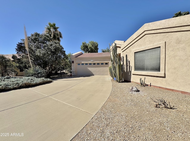 view of front of property with concrete driveway, a tile roof, an attached garage, and stucco siding