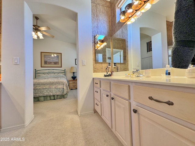 ensuite bathroom featuring baseboards, ceiling fan, vanity, and ensuite bath