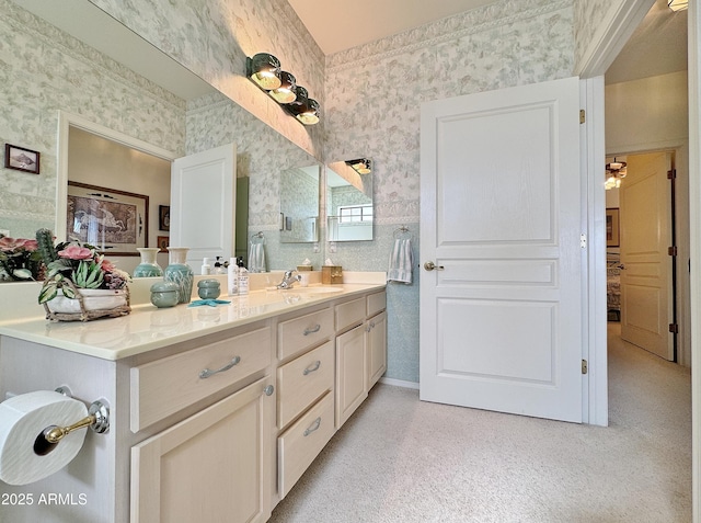 bathroom with wallpapered walls, baseboards, and vanity