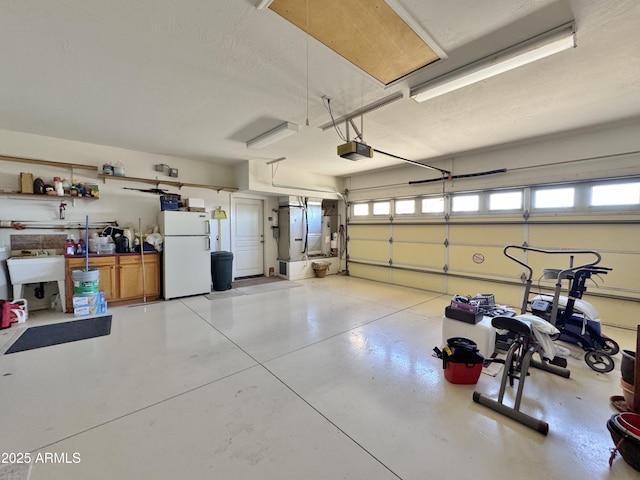 garage featuring a garage door opener, freestanding refrigerator, and a sink