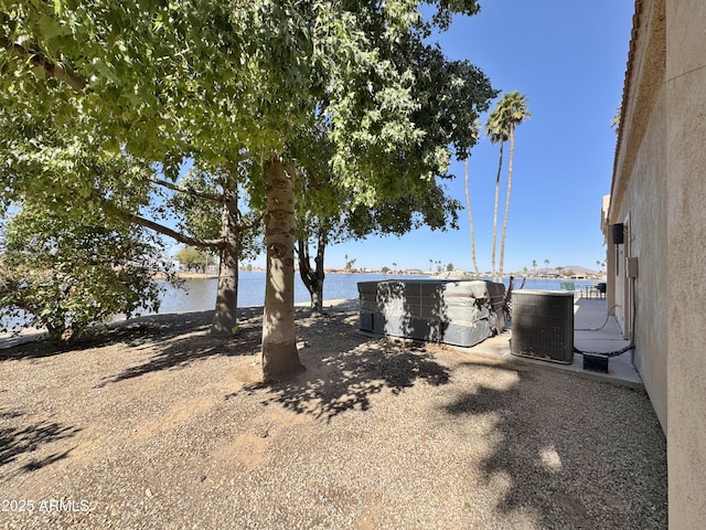 view of yard with a water view and central air condition unit