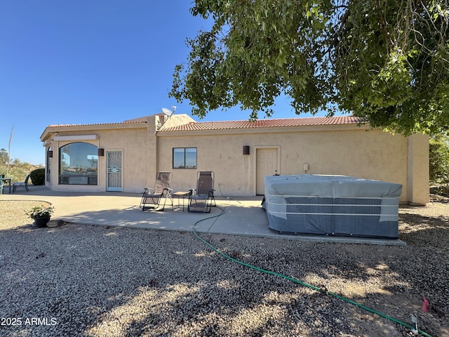 back of house with a patio area, a tiled roof, central AC unit, and stucco siding