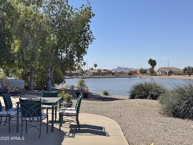 view of patio featuring a water view, a residential view, and outdoor dining space