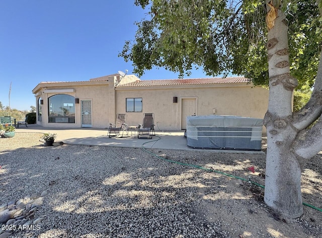 rear view of house with central air condition unit, a patio area, a tile roof, and stucco siding