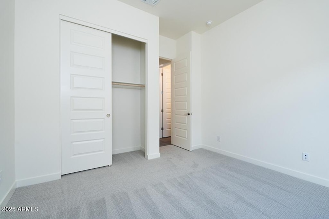 unfurnished bedroom featuring light carpet and a closet