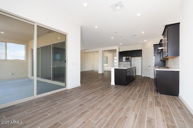 kitchen with tasteful backsplash, hardwood / wood-style flooring, stainless steel microwave, and a kitchen island