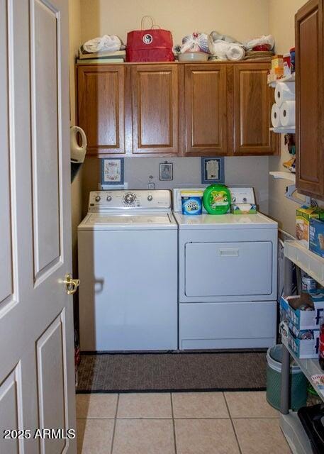 laundry room with cabinets, light tile patterned floors, and independent washer and dryer