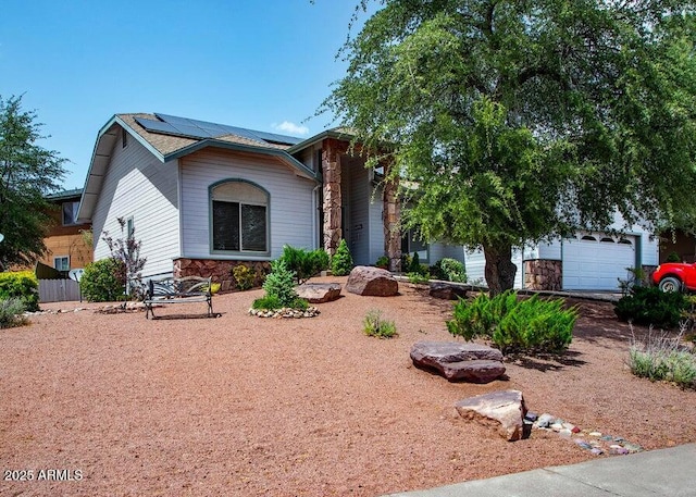 view of front of house with solar panels, a garage, and stone siding