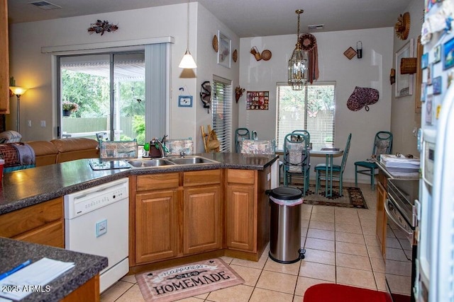 kitchen with sink, white appliances, hanging light fixtures, a healthy amount of sunlight, and light tile patterned flooring