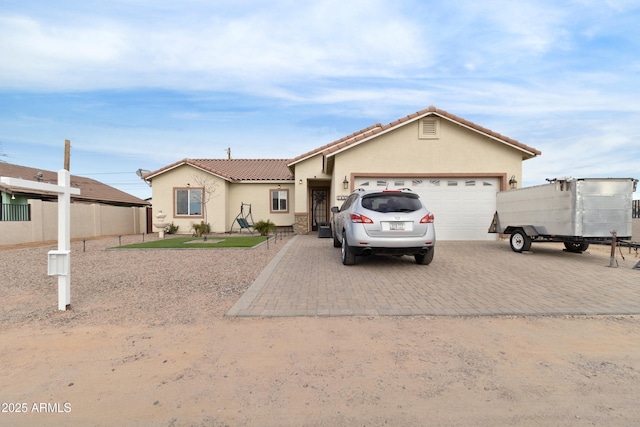 view of front of house featuring a garage, decorative driveway, a tile roof, and stucco siding