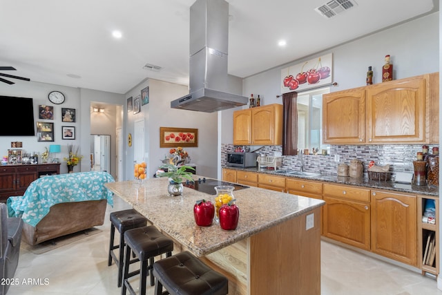 kitchen featuring sink, island range hood, a kitchen island, and stone countertops