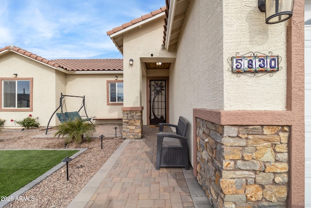 property entrance featuring a tile roof and stucco siding