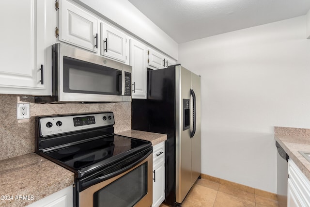 kitchen featuring white cabinets, light tile patterned floors, stainless steel appliances, and tasteful backsplash