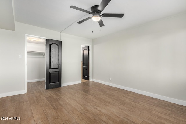 unfurnished bedroom with hardwood / wood-style floors, ceiling fan, a spacious closet, and a closet