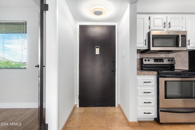 kitchen with appliances with stainless steel finishes, light tile patterned floors, and white cabinetry