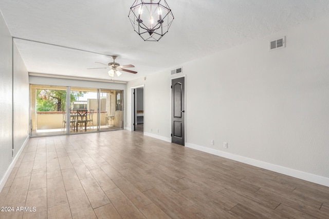 unfurnished room featuring ceiling fan with notable chandelier and wood-type flooring