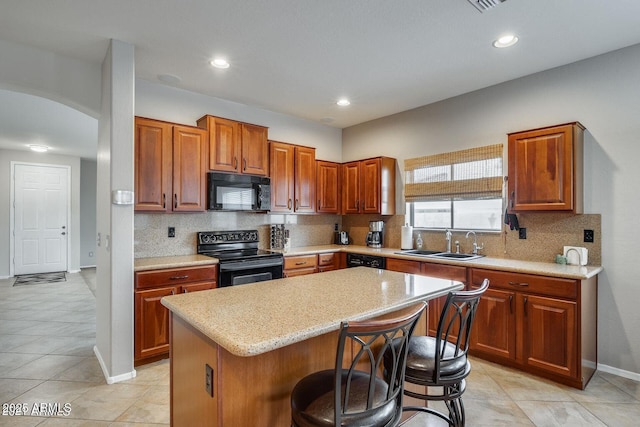 17562 W Agave Ct, Goodyear, AZ 85338 - kitchen featuring black appliances, a sink, a kitchen breakfast bar, backsplash, and a kitchen island