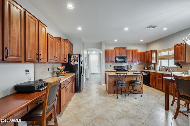 17562 W Agave Ct, Goodyear, AZ 85338 - kitchen featuring black appliances, a sink, a breakfast bar area, backsplash, and recessed lighting