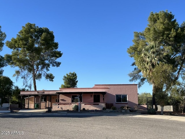 ranch-style home featuring stucco siding and fence
