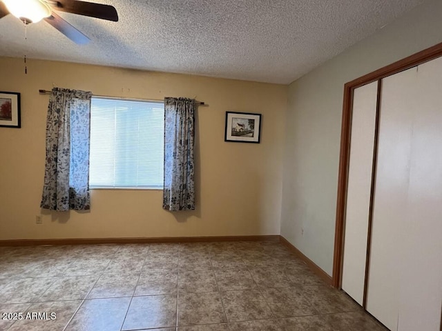 empty room with baseboards, ceiling fan, and a textured ceiling