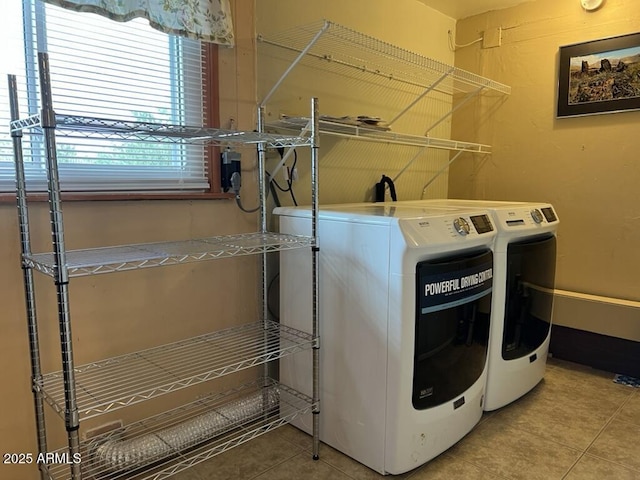 clothes washing area featuring tile patterned floors, washer and dryer, and laundry area