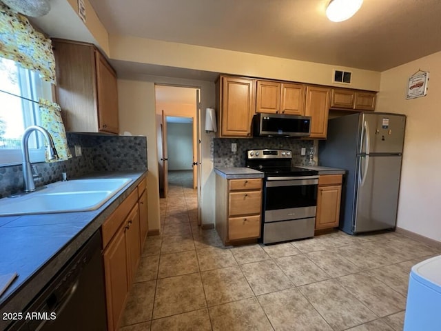 kitchen featuring light tile patterned floors, a sink, visible vents, stainless steel appliances, and backsplash