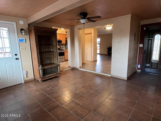 entryway with a ceiling fan, dark tile patterned floors, and baseboards