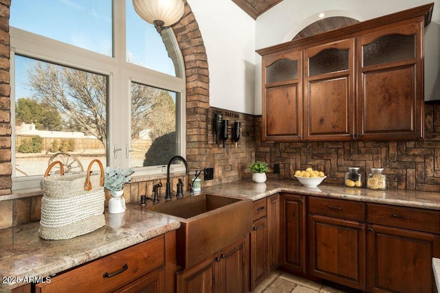 kitchen with light stone counters, sink, and backsplash