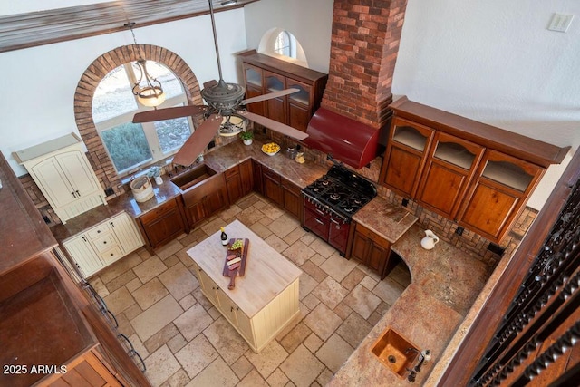 kitchen featuring sink, ceiling fan, black gas cooktop, a high ceiling, and decorative light fixtures