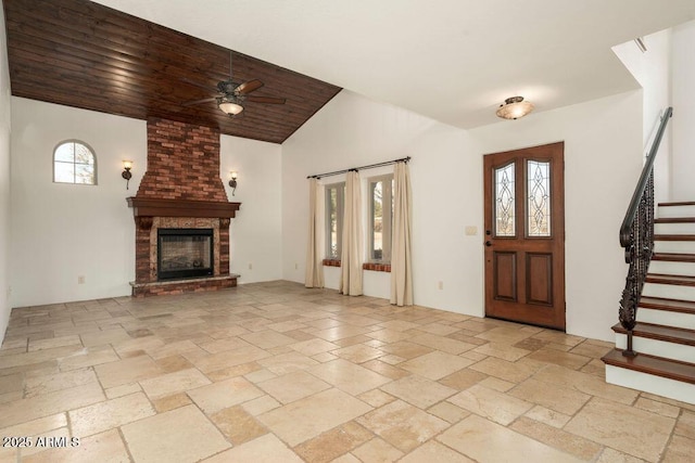 entryway featuring ceiling fan, a fireplace, vaulted ceiling, and wooden ceiling