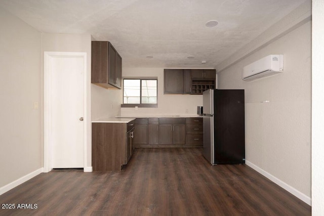 kitchen featuring dark brown cabinets, a wall unit AC, dark wood-type flooring, and stainless steel refrigerator