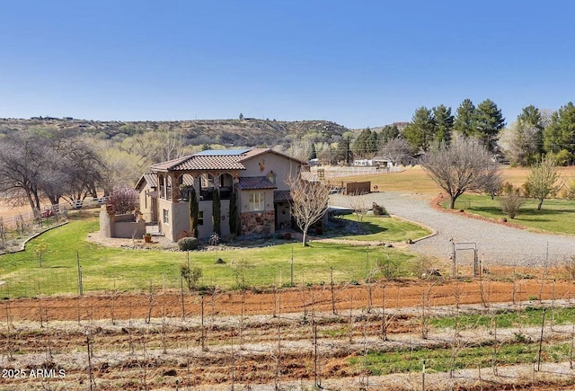 back of property with a rural view, a mountain view, and a lawn