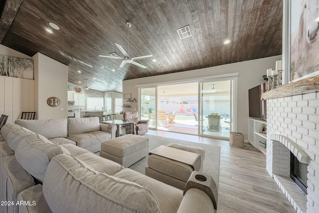 living room with lofted ceiling, ceiling fan, light wood-type flooring, a fireplace, and wood ceiling