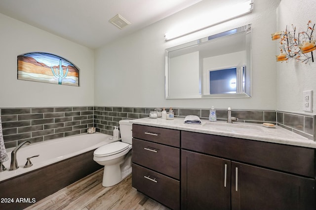 bathroom with hardwood / wood-style flooring, vanity, toilet, and a bath