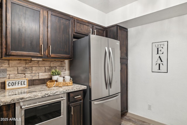 8787 E Mountain View Rd Unit 2100, Scottsdale, AZ 85258 - kitchen with freestanding refrigerator, dark brown cabinets, tasteful backsplash, light stone countertops, and baseboards