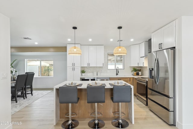 kitchen featuring a breakfast bar, visible vents, white cabinets, appliances with stainless steel finishes, and tasteful backsplash