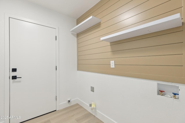 laundry room featuring laundry area, wooden walls, baseboards, light wood-type flooring, and washer hookup