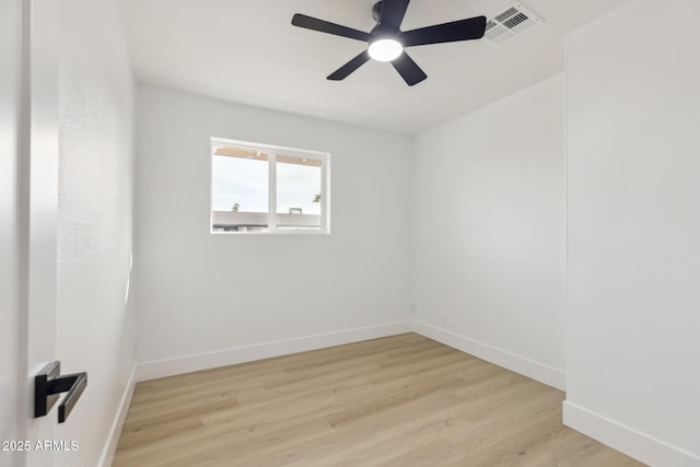 spare room with a ceiling fan, visible vents, baseboards, and wood finished floors