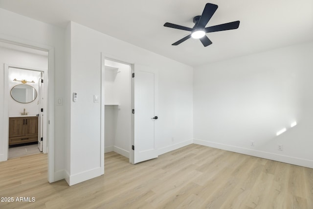 unfurnished bedroom featuring baseboards, ceiling fan, a spacious closet, light wood-type flooring, and a closet